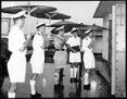 Twiss and inspecting team with umbrellas in heavy rain c.1967.